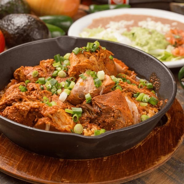 El Vaquero's Mexican pork carnitas with rice and green onions, with a side of refried beans.