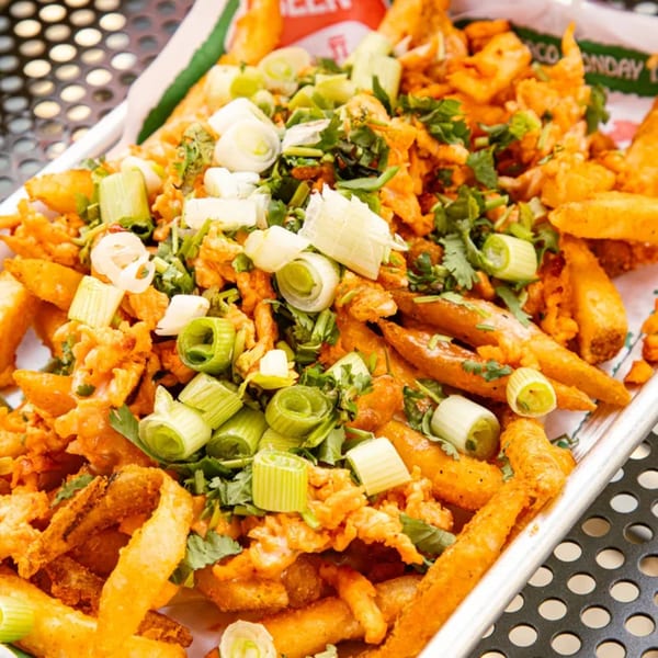 El Vaquero's Mexican fries topped with green onions, cilantro, and a creamy orange sauce.