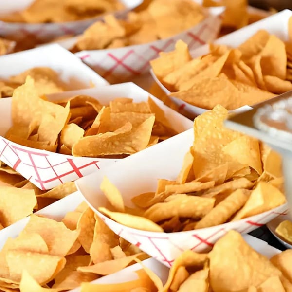 Multiple paper boats filled with golden, crispy tortilla chips, ready to be served at El Vaquero.