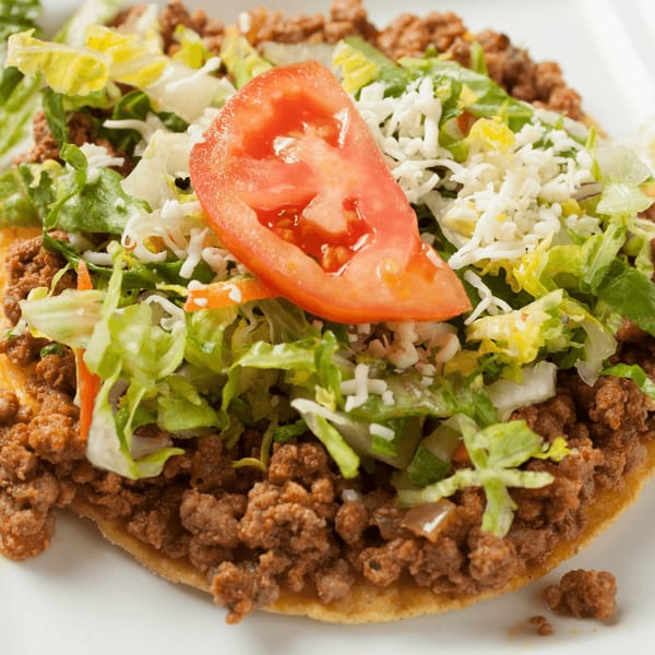 El Vaquero's tostada with seasoned ground beef, shredded lettuce, cheese, and a tomato slice.