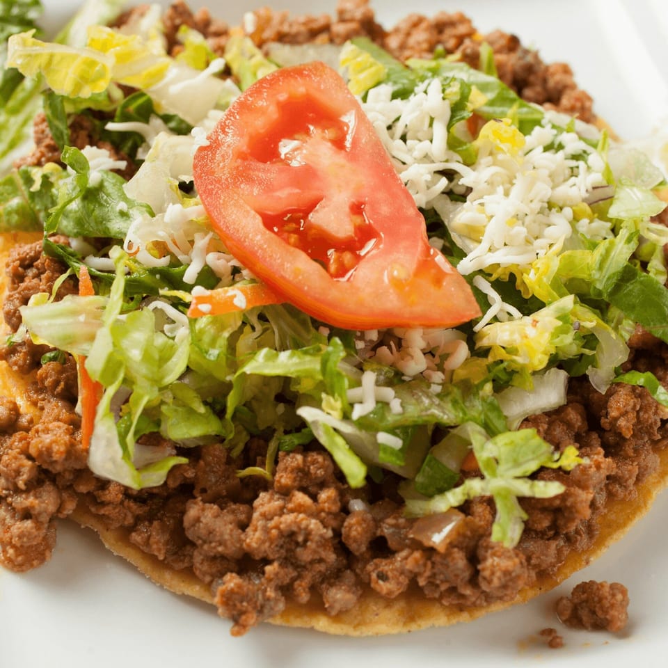 El Vaquero's tostada with seasoned ground beef, shredded lettuce, cheese, and a tomato slice.