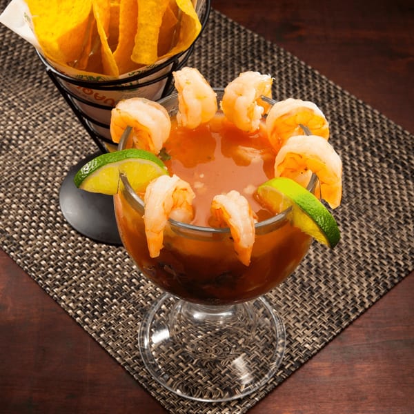 El Vaquero's shrimp cocktail with lime wedges and a side of tortilla chips.