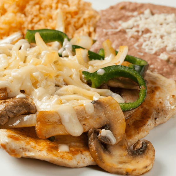 El Vaquero's chicken dish with melted cheese, mushrooms, green peppers, onions, rice, and refried beans.