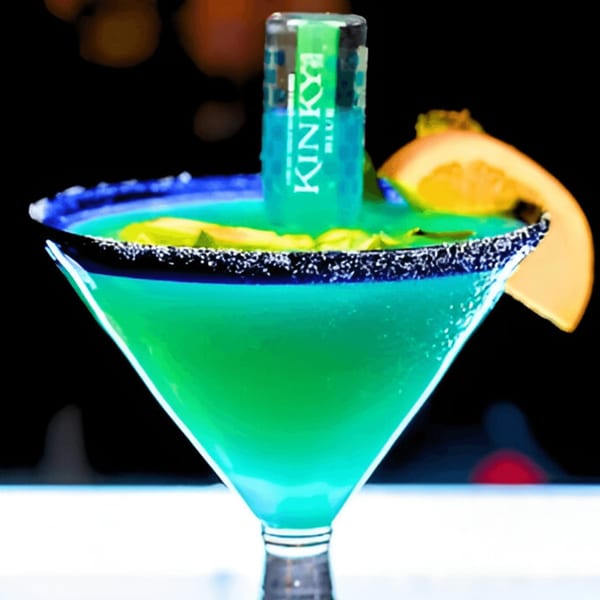 A vibrant blue-green margarita in a martini glass, garnished with a Kinky Blue shot and orange slice.