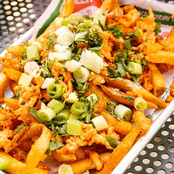 El Vaquero's Mexican fries, topped with green onions, cilantro, and a creamy orange sauce.