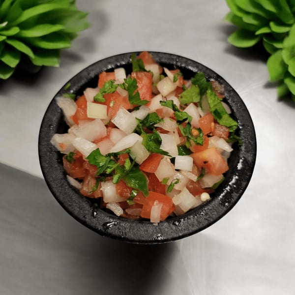 Fresh pico de gallo with diced tomatoes, onions, and cilantro in a dark bowl.