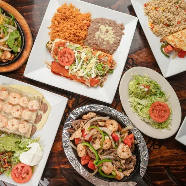 A top-down view of various Mexican dishes, including enchiladas, fajitas, and shrimp burritos.