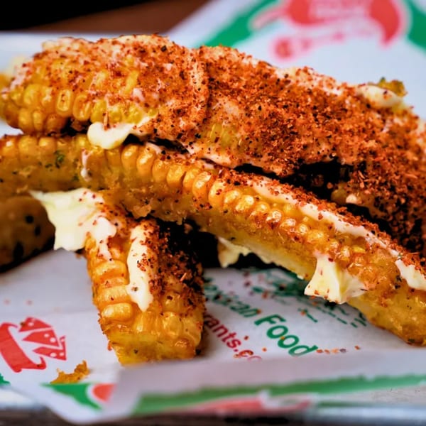 El Vaquero's Mexican street corn, elote, with mayonnaise and chili powder on a branded paper.